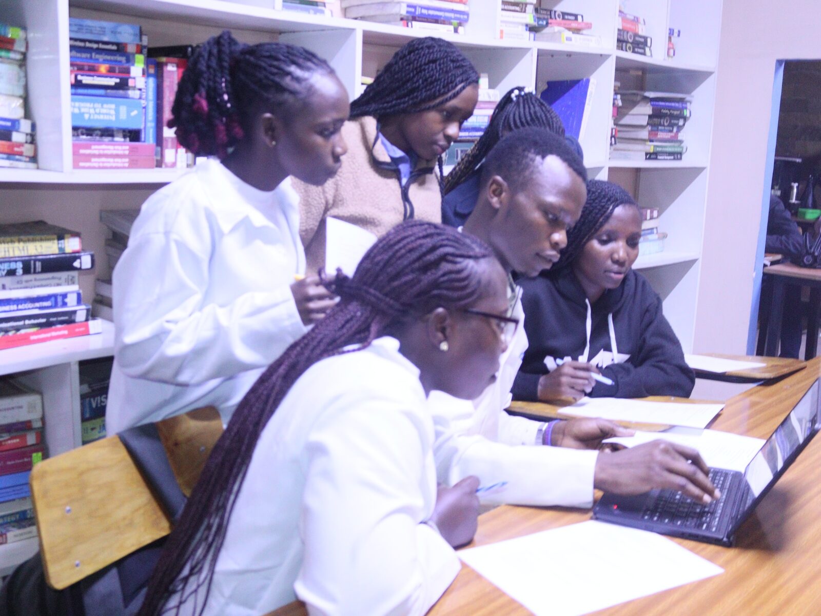 Topmax students collaborating with a laptop in the library